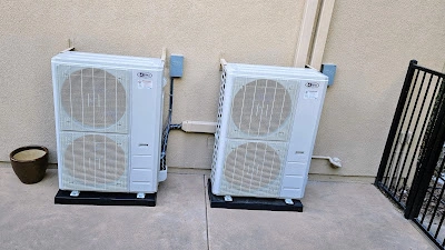 Two air conditioners positioned on a concrete patio